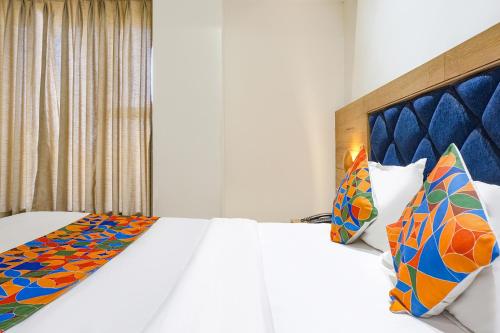 a bedroom with a large white bed with colorful pillows at FabHotel Pancharatna Regency - Nr Medicover Hospital in Pune