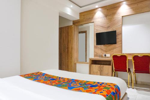 a bedroom with a bed and two red chairs at FabHotel Pancharatna Regency - Nr Medicover Hospital in Pune