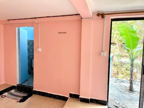 a bathroom with a pink wall and a glass door at Garden Bungalows Koh Rong in Koh Rong