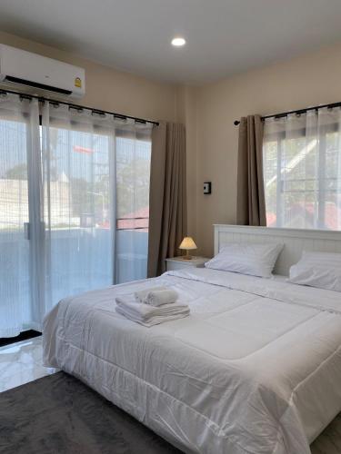a bedroom with a large white bed with windows at Ta-iad homestay at Soi Ta-iad in Ban Suan