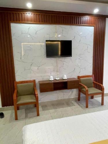 a room with two chairs and a tv on a stone wall at HQ Hotel & Apartment in Hai Phong