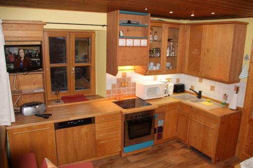 a kitchen with wooden cabinets and a microwave at Ferienwohnung Edelweiss in Bischofsgrün