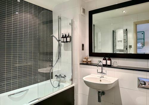 a bathroom with a sink and a shower with a mirror at The Ridings at Theobalds Park in Goffs Oak