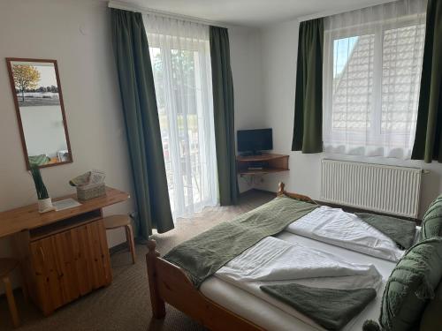 a bedroom with a bed and a mirror and windows at VillaBoglár in Balatonboglár