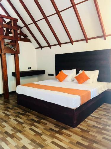 a bedroom with a large bed with orange and white pillows at The Hideaway Sigiriya in Sigiriya