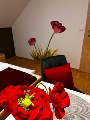 a room with a table with red flowers on it at Fremdenzimmer Pehn in Ottenschlag