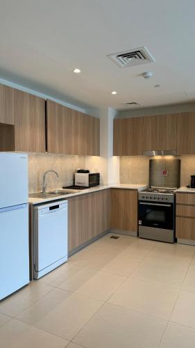 a large kitchen with white appliances and wooden cabinets at Светлая и просторная квартира in Sharjah