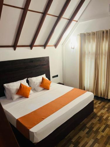 a bedroom with a large bed with orange pillows at The Hideaway Sigiriya in Sigiriya