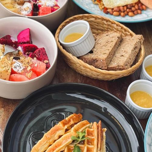 un tavolo con piatti di cibo e ciotole di pane di Aloka Penida a Klungkung