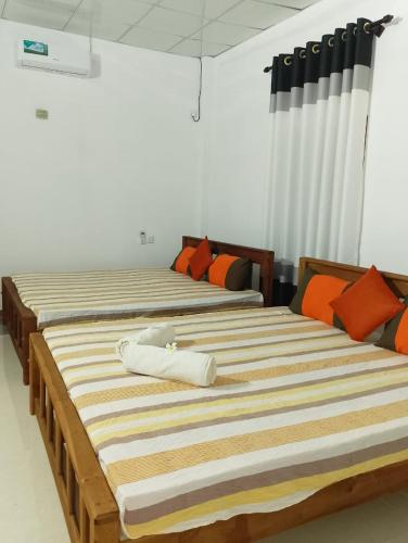two beds in a room with orange pillows at Rock Hill in Tanamalwila