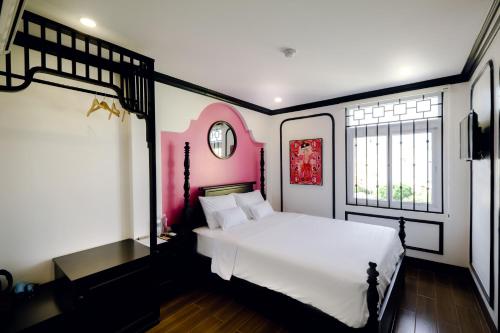 a bedroom with a large white bed and two windows at The Fancy House in Quy Nhon