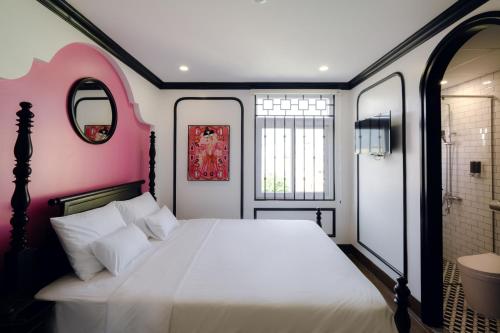 a bedroom with a white bed and a pink wall at The Fancy House in Quy Nhon
