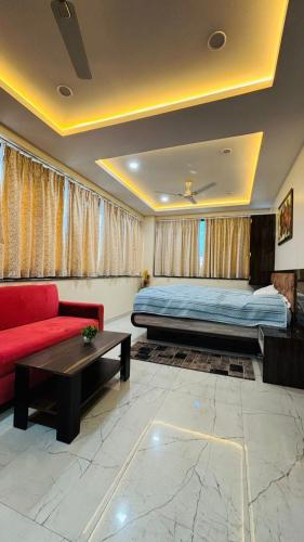 a living room with a bed and a red couch at Hotel Vivaanta in Dhanbād