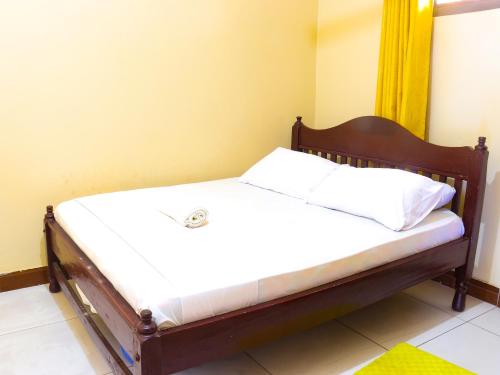 a bed with white sheets and a wooden frame at Beach Road Luxury Homes in Mombasa