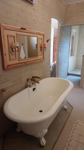 a large white tub in a bathroom with a mirror at Hartland Country House Luxury Double Rooms in Oudtshoorn