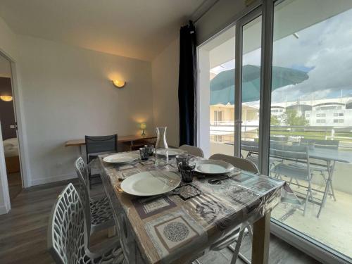 une table de salle à manger avec des chaises et une grande fenêtre dans l'établissement Appt 2 pièces LA ROCHELLE - LR030-B225Z, à La Rochelle