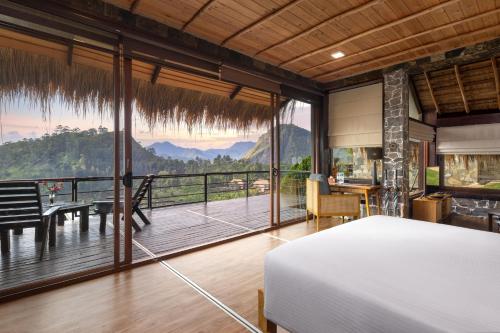 a bedroom with a bed and a balcony with a table at 98 Acres Resort & Spa in Ella