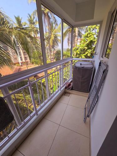 a balcony with views of palm trees and a trash can at Cozy Apt Easy Access - Groceries & Transport in Mangalore