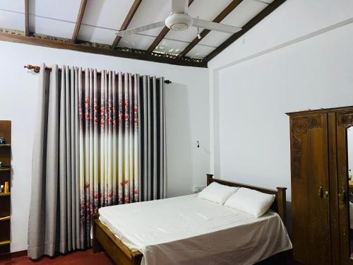 a bedroom with a bed with white sheets and a window at Wakishta Villa - Weligama in Weligama