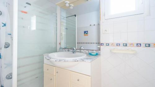 une salle de bain blanche avec un lavabo et une douche dans l'établissement Le Lamparo N201 - 2P4, au Cap d'Agde