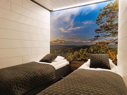 two beds in a room with a large window at Pärjä Suites 2 in Syöte