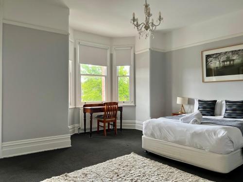 a bedroom with a bed and a desk and a chair at Charming Heritage Home in Launceston
