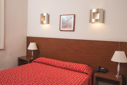 a bedroom with a red bed with a red bedspread at Gran Hotel Victoria Cordoba Argentina in Cordoba