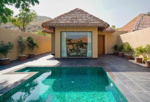 a villa with a swimming pool in front of a house at Tree of Life Amara Resorts & Spa, Udaipur in Udaipur