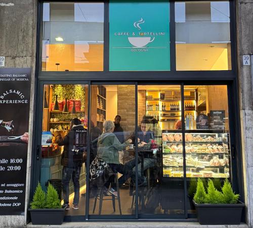 un gruppo di persone sedute ai tavoli nella vetrina di un negozio di Bilocale Amendola 13 a Bologna