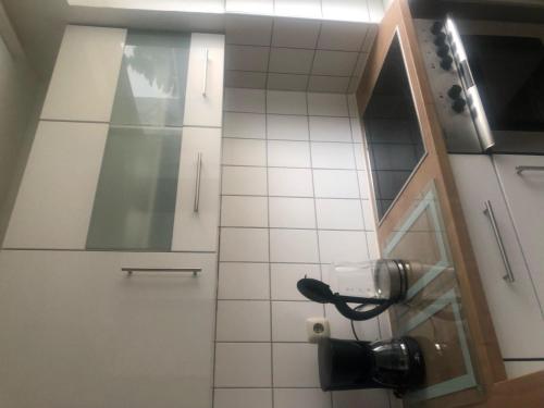 a small white tiled bathroom with a phone at Ferienwohnung Folke-Bernadotte in Lübeck