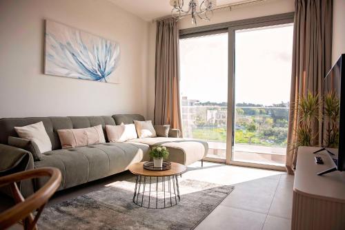 a living room with a couch and a large window at Blue Oasis Apartment in Nea Paphos