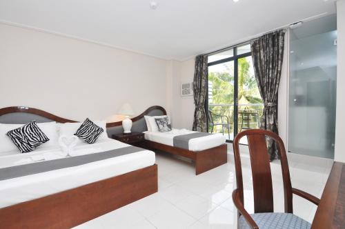a bedroom with two beds and a chair and a window at 717 Cesar Place Hotel in Tagbilaran City