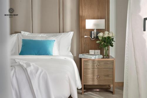 a bed with a blue pillow and a night stand with a lamp at Moonlight Bay Panorama Condotel Ocean View in Nha Trang