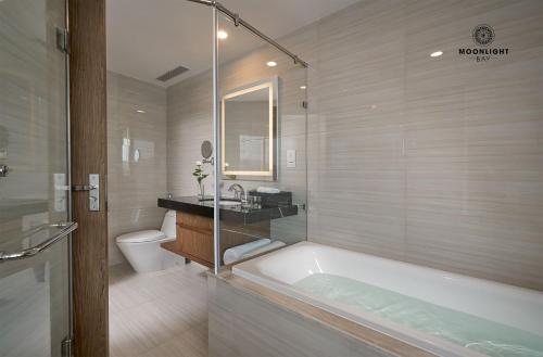 a bathroom with a tub and a sink and a toilet at Moonlight Bay Panorama Condotel Ocean View in Nha Trang