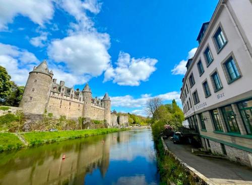 a castle with a river in front of a building at Gîte de l Archange in Josselin