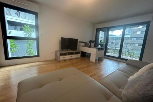 un salon avec un canapé blanc et une télévision dans l'établissement Spacious appt with balcony in the 13th, à Paris