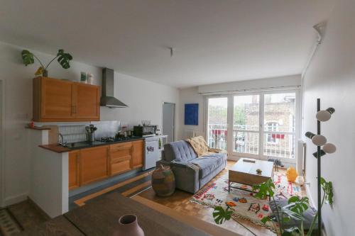 un salon avec un canapé et une cuisine dans l'établissement Charming apartment in Buttes Chaumont, à Paris