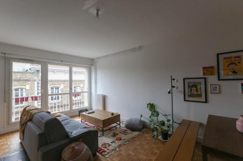 un salon avec un canapé et une grande fenêtre dans l'établissement Charming apartment in Buttes Chaumont, à Paris