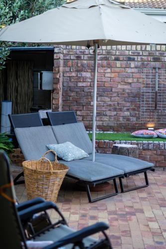 a picnic table with an umbrella on a patio at Earthbound Guest House in Oudtshoorn