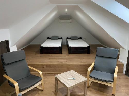 a attic room with two beds and a table and chairs at Spacious Apartment in Town Centre in Nové Zámky