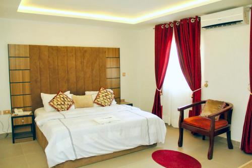 a bedroom with a large white bed and a chair at Cogent Apartments in Uyo