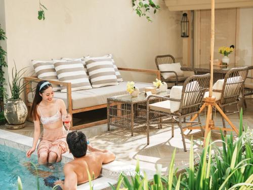 a man and a woman sitting in a swimming pool at Villa ALANNA in Chiang Mai