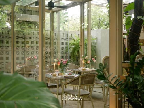 a dining room with tables and chairs and windows at Villa ALANNA in Chiang Mai