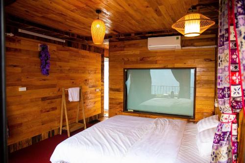 a bedroom with a large screen television in a wooden wall at Mây home Trạm Tấu bungalow in Ya Ló