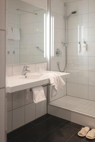 a white bathroom with a sink and a shower at Rheinhotel Dreesen in Bonn