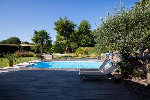 - une piscine avec 2 chaises longues dans la cour dans l'établissement Wine Hôte Chambre d'hôtes, à Le Pian-Médoc