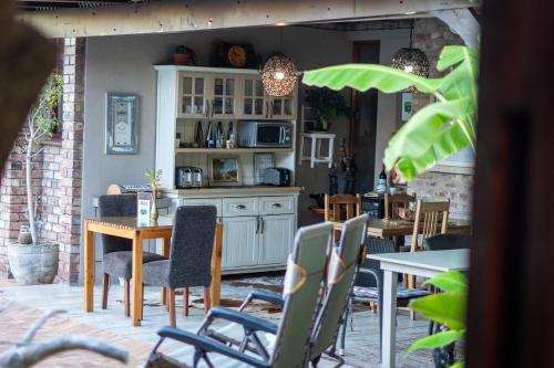 a kitchen and dining room with tables and chairs at Earthbound Guest House in Oudtshoorn