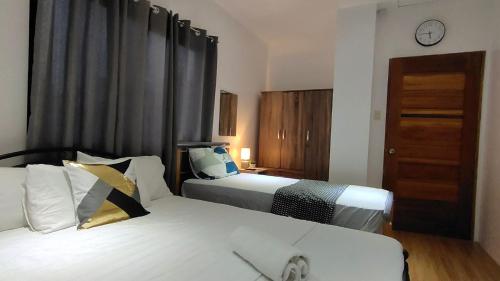 a hotel room with two beds and a clock on the wall at Ormoc Mountain View Apartment in Ormoc