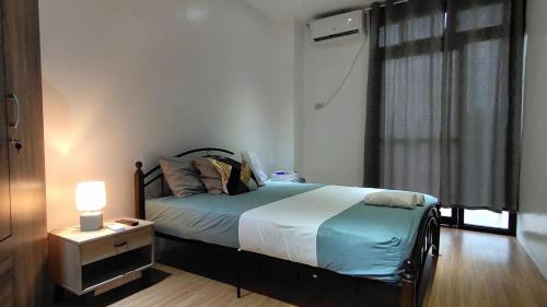 a bedroom with a bed with a night stand and a window at Ormoc Mountain View Apartment in Ormoc