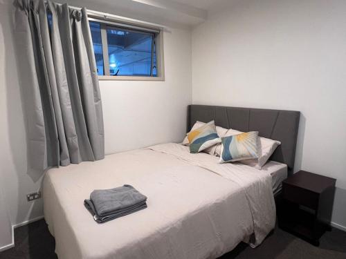 a bedroom with a bed with a bag on it at Aura C two bedrooms apartment balcony good view wi-fi easy parking in Auckland